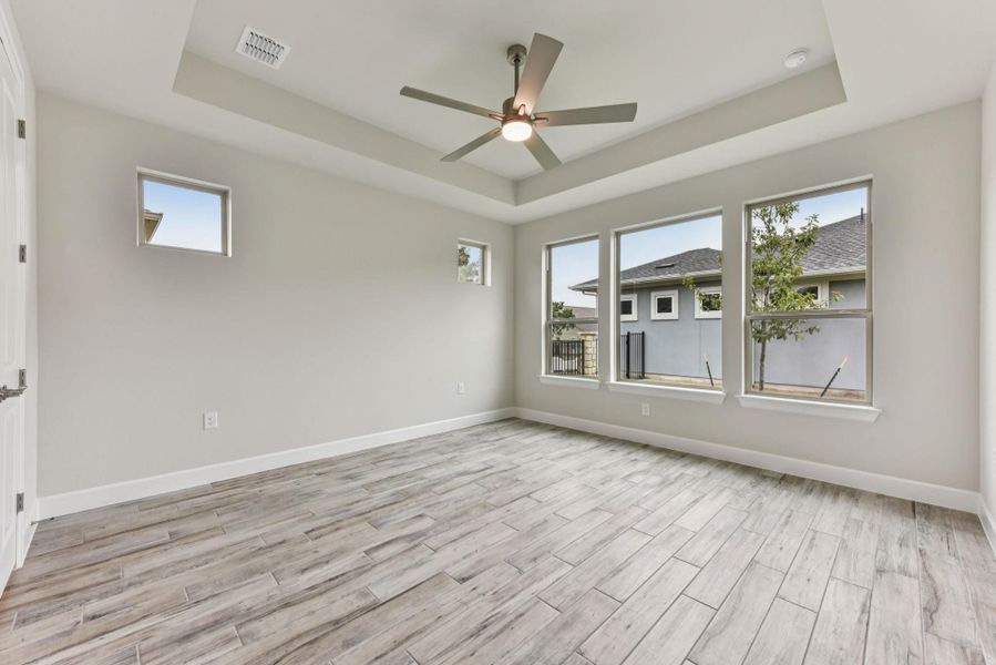 Unfurnished room with a raised ceiling, ceiling fan, and wood tiled floors