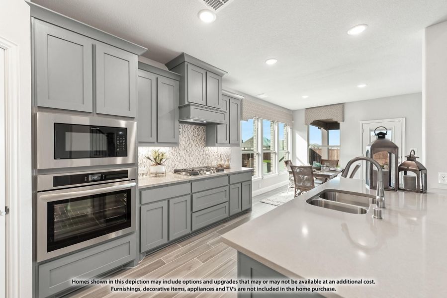 Kitchen with gray cabinets, stainless steel appliances, tile backsplash, and large island with sink Kitchen with gray cabinets, stainless steel appliances, tile backsplash, and large island with sink