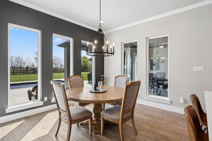 Dining space featuring hanging lights, wood finished floors, and ornamental molding