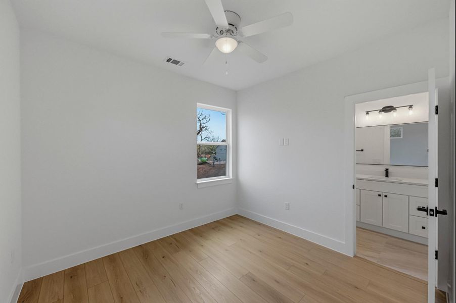 Unfurnished bedroom featuring light wood-style floors, a ceiling fan, and connected bathroom