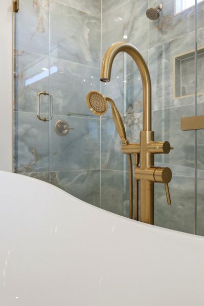 Elegant gold hardware pairs beautifully with patterned tile inside this modern shower and tub area.