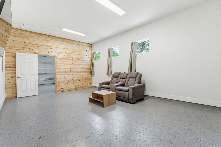 A versatile open-plan space boasts durable flooring, an inviting wood accent wall, and bright lighting.