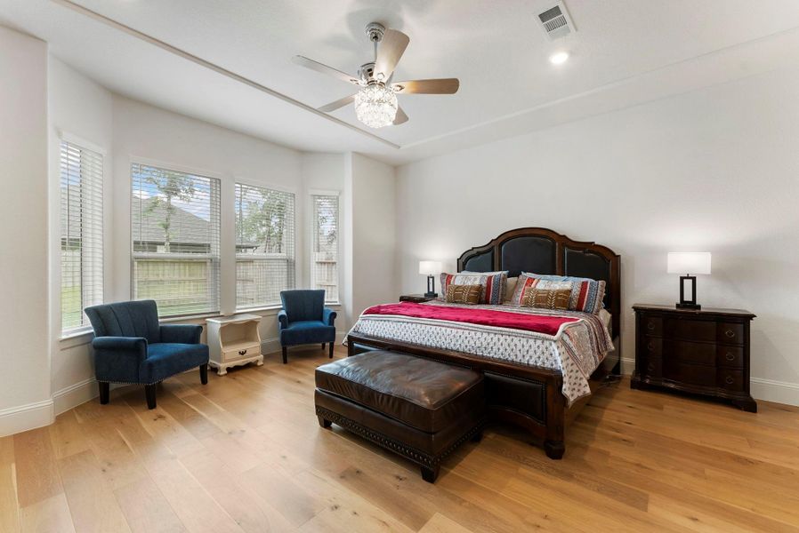The spacious primary bedroom offers a cozy bay window sitting area and stylish fandelier.