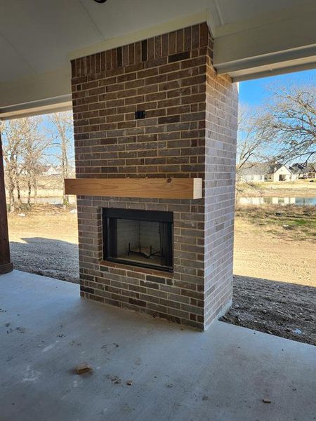 View of patio with an outdoor brick fireplace