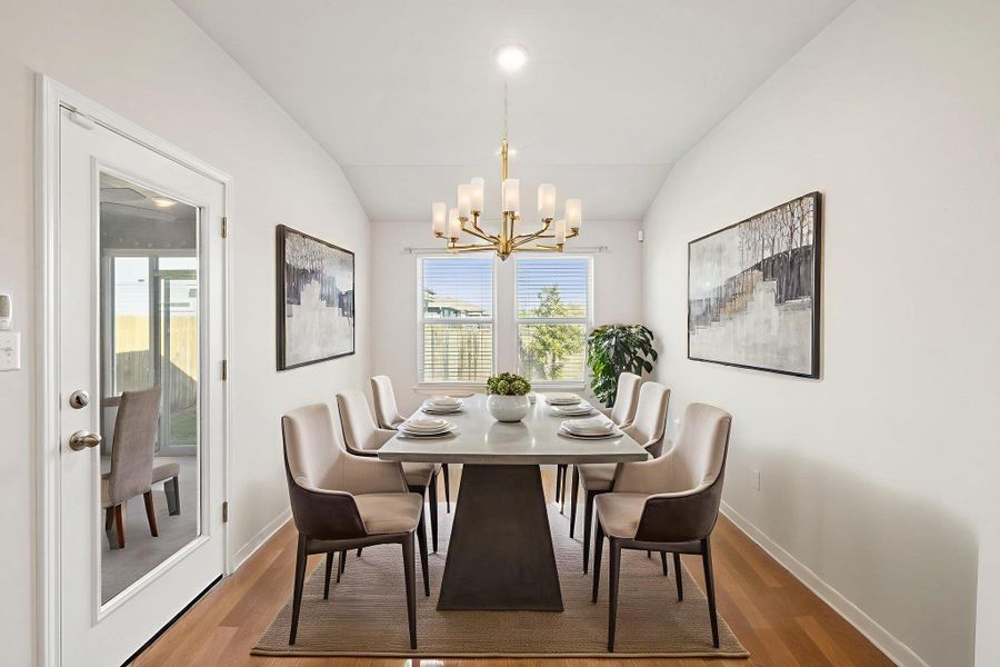 Dining room with lofted ceiling, wood finished floors, and a chandelier Dining room with lofted ceiling, wood finished floors, and a chandelier