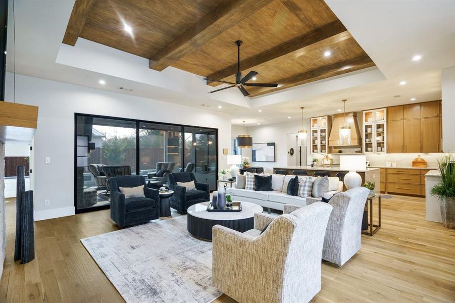 Warm and inviting living room, ceiling fan, wood paneled ceiling, and stunning hardwood flooring