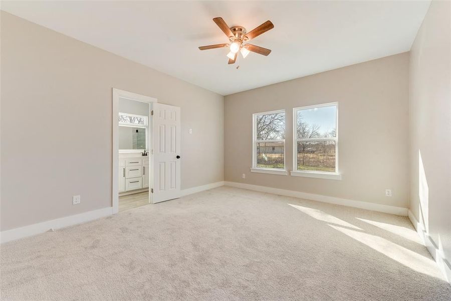 Unfurnished bedroom featuring ensuite bathroom, light carpet, and ceiling fan