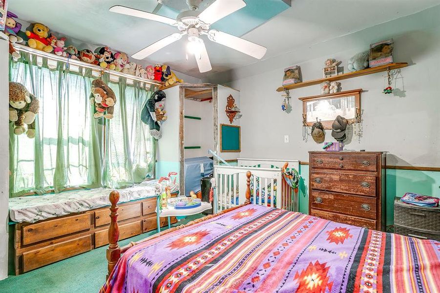 Bedroom featuring a crib, carpet floors, and a ceiling fan Bedroom featuring a crib, carpet floors, and a ceiling fan