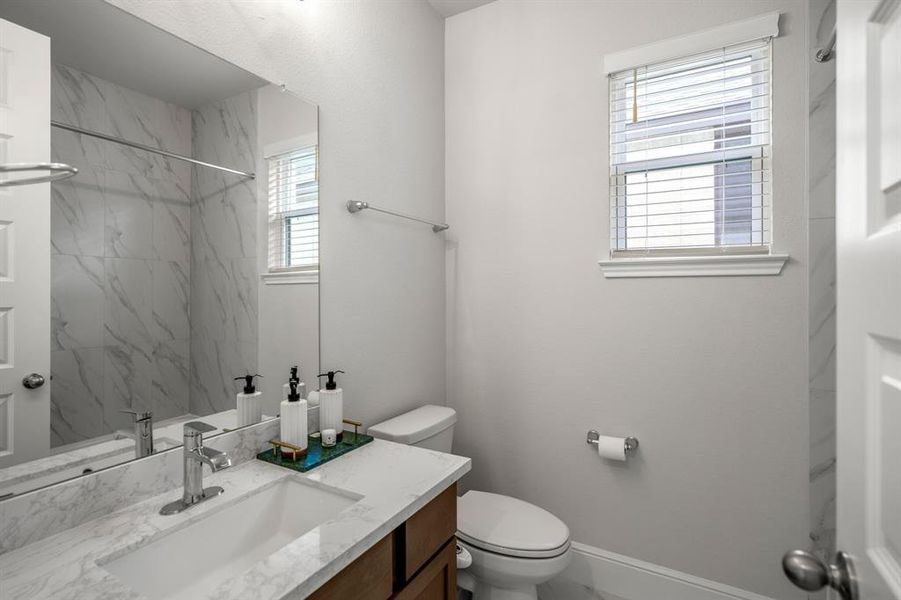 Located just off the secondary bedroom and game room, this full bathroom is complete with a combination tub and shower, wood cabinets, quartz countertops and modern tile.