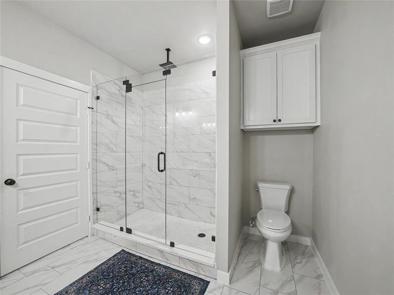 Spacious shower with glass enclosure and black hardware, complemented by large format tile flooring and shower surround Spacious shower with glass enclosure and black hardware, complemented by large format tile flooring and shower surround