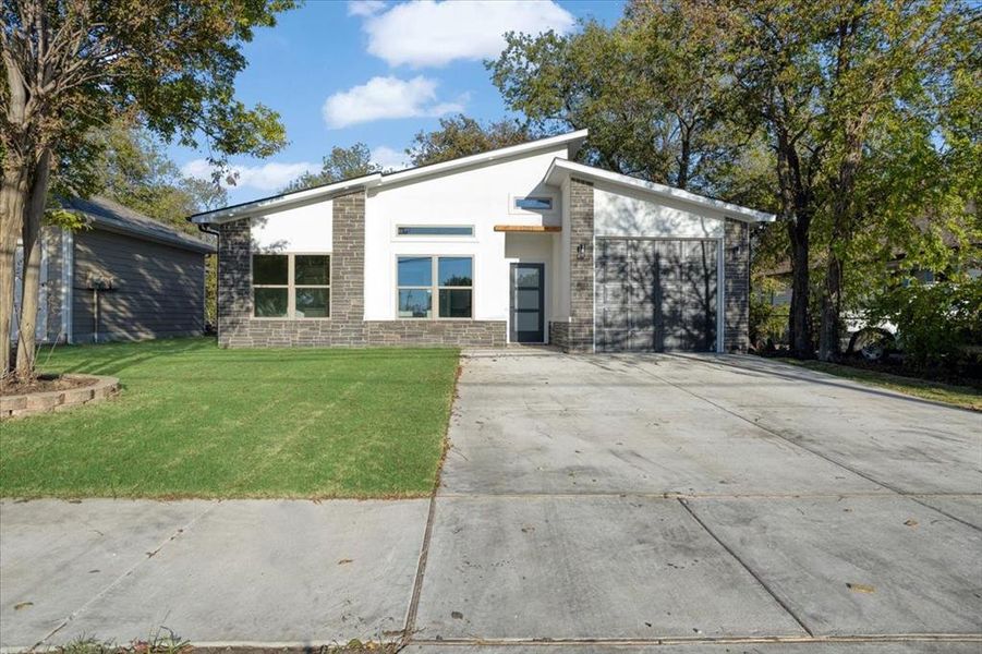 Modern home featuring a front yard and a garage