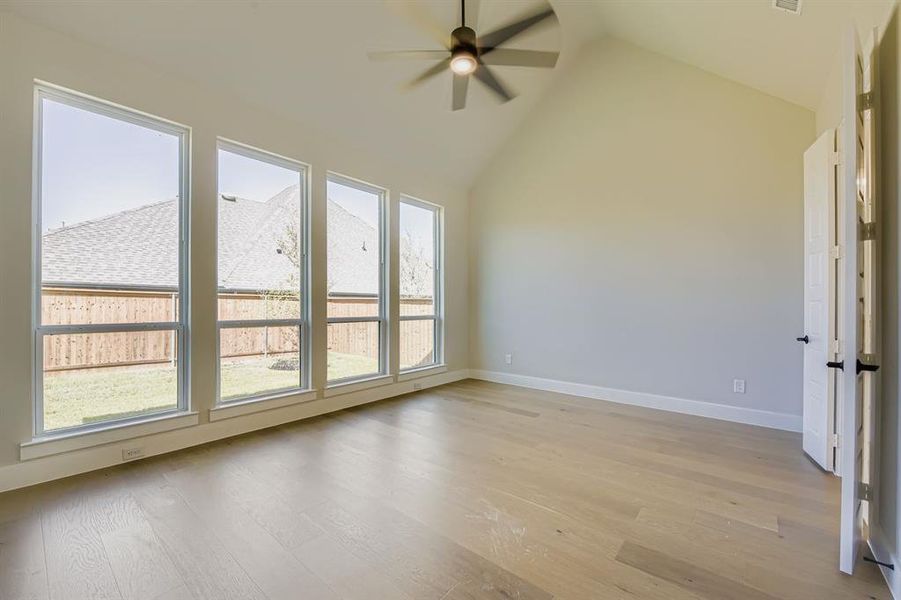 Spare room with ceiling fan, light wood-style flooring, and high vaulted ceiling