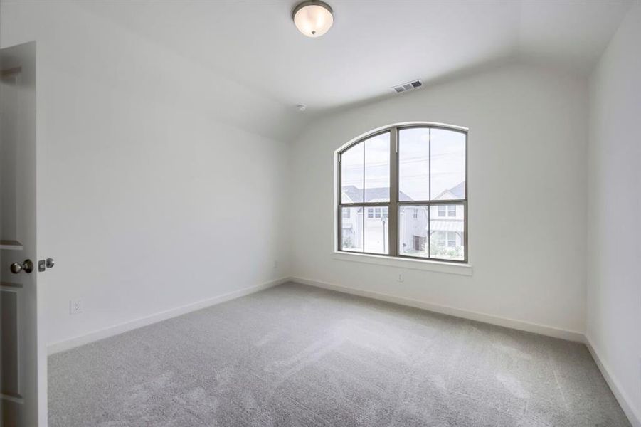 Room featuring an arched window, vaulted ceiling, neutral wall paint, and gray carpeting Room featuring an arched window, vaulted ceiling, neutral wall paint, and gray carpeting