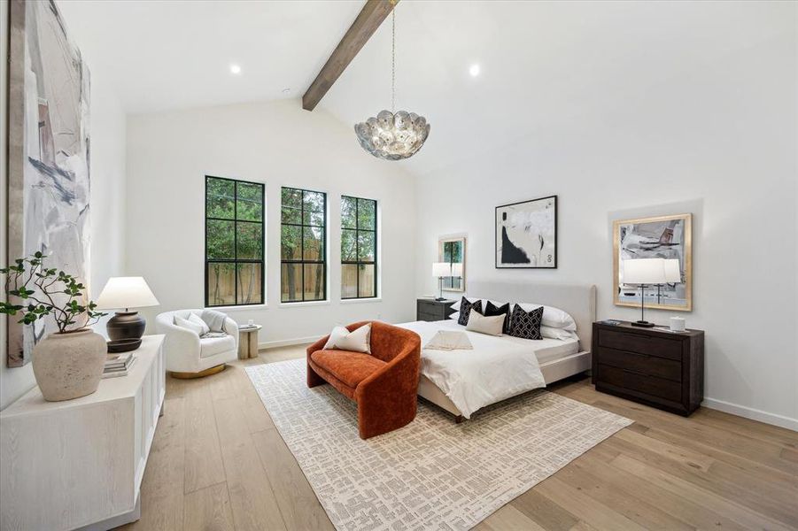 The spacious first floor primary bedroom features vaulted ceilings with exposed beams and large windows that overlook the private backyard, creating a serene retreat.