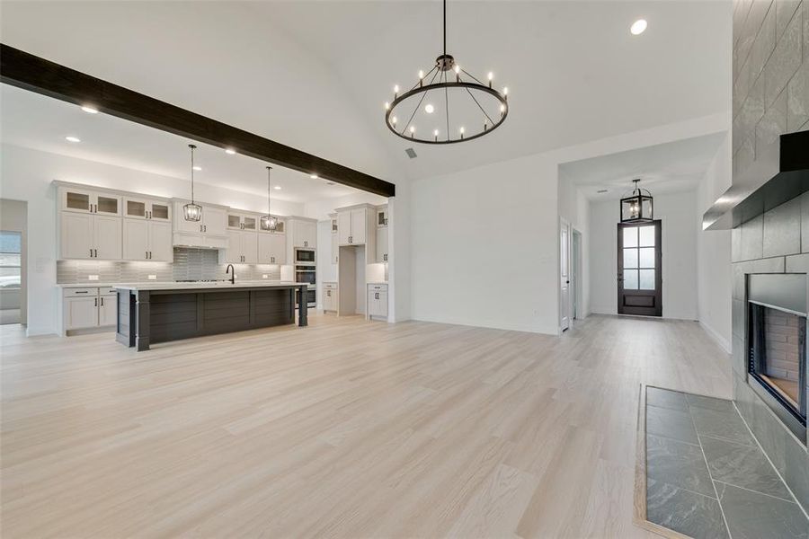 Unfurnished living room with light hardwood / wood-style flooring, a notable chandelier, sink, and a tile fireplace