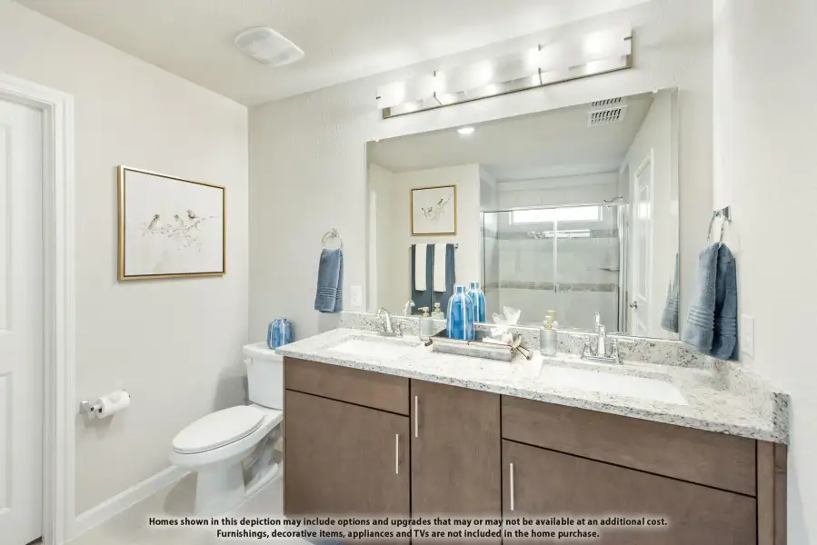 Bathroom with double sink vanity, granite countertop, dark wood cabinets, and glass shower enclosure