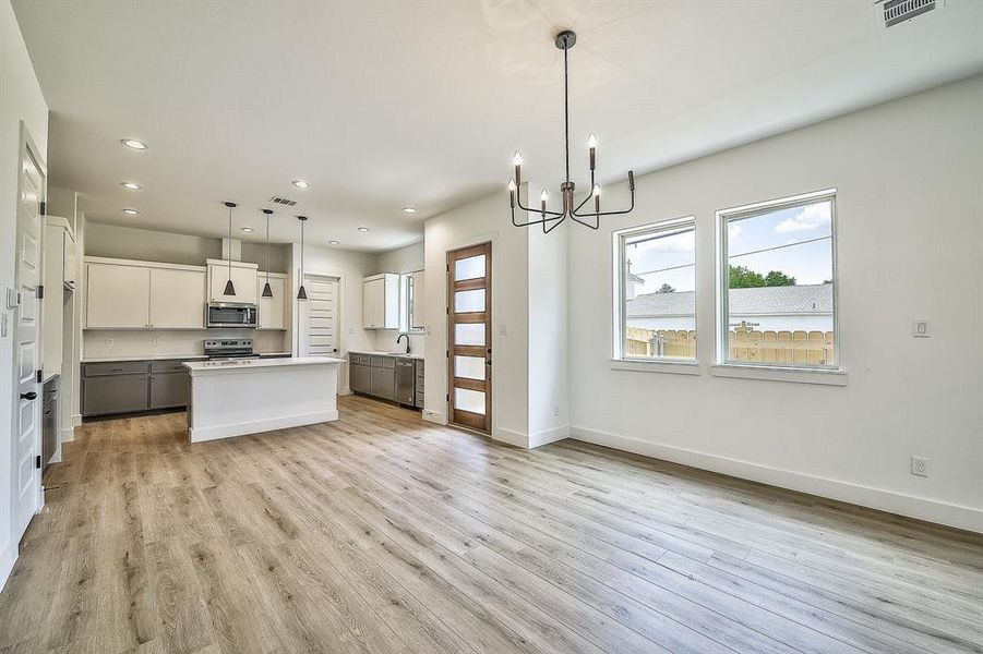 Kitchen with pendant lighting, stainless steel appliances, a center island, and white cabinetry