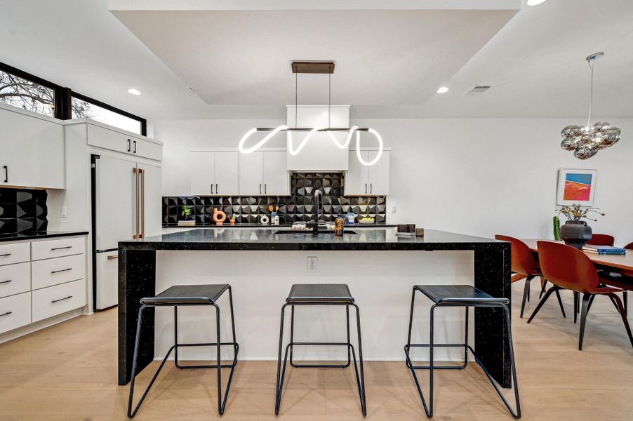 Kitchen featuring backsplash, white cabinetry, a large island with sink, dark stone countertops, and recessed lighting