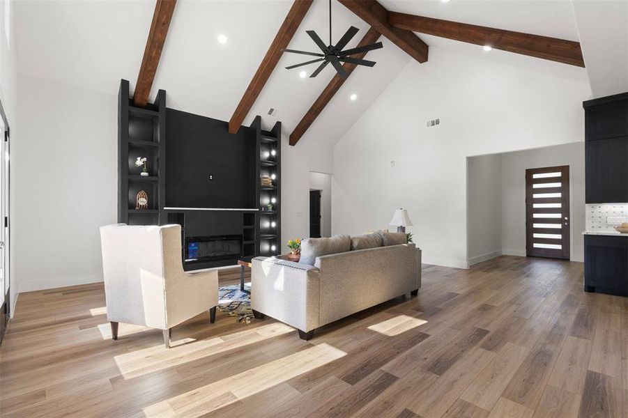 Living room featuring high vaulted ceiling, a glass covered fireplace, light wood-style flooring, recessed lighting, and a ceiling fan