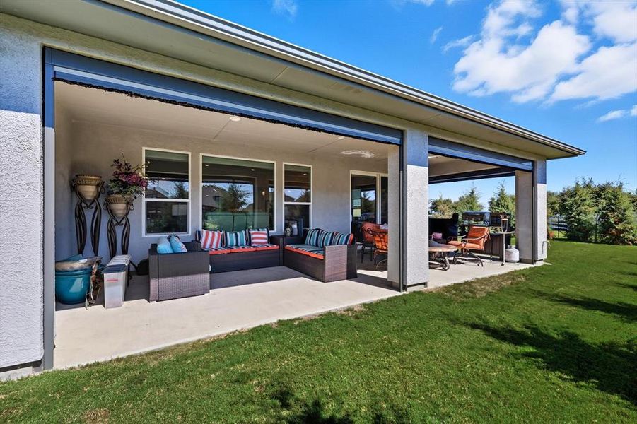 Spacious covered patio with concrete flooring, multiple overhead recessed light fixtures, and a large grassy area