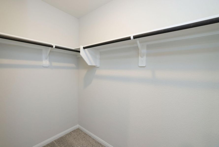This photo shows a spacious walk-in closet with double hanging rods and light-colored walls.