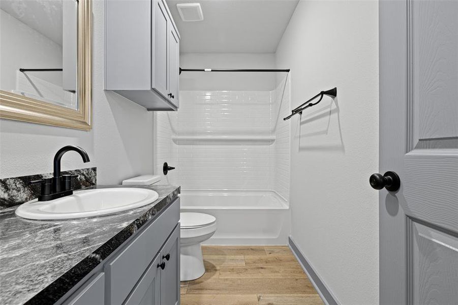Full bathroom featuring light wood-type flooring, vanity, and shower / washtub combination Full bathroom featuring light wood-type flooring, vanity, and shower / washtub combination