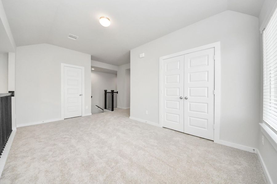 Come upstairs and relish a day of relaxation in this loft area! Ideal as an additional living space or game room, it boasts plush carpeting, high ceilings, custom paint, and windows that flood the area with abundant natural light. Sample photo of completed home with similar floor plan. Actual colors and selections may vary.