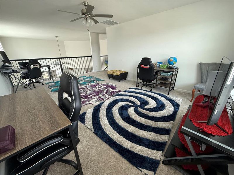 Spacious loft area featuring neutral carpeting and a ceiling fan with integrated lighting