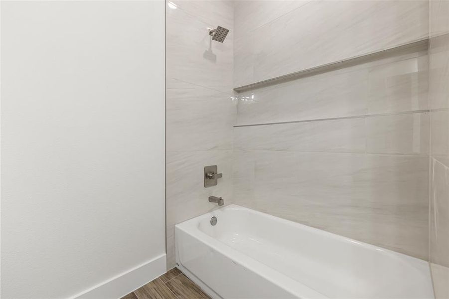 Bathroom featuring hardwood / wood-style flooring and tiled shower / bath combo