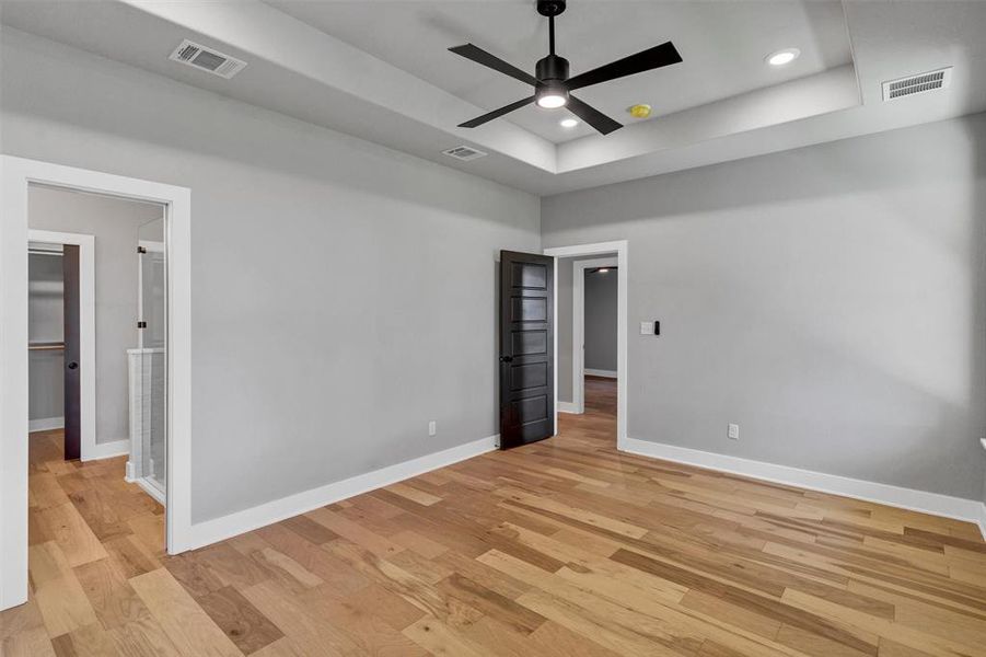 Unfurnished room with light wood finished floors, a tray ceiling, recessed lighting, and ceiling fan
