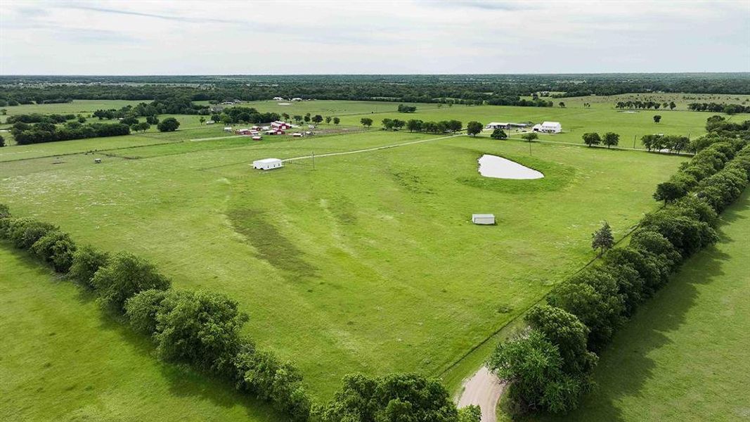 Expansive green pastures with a natural pond and mature tree lines