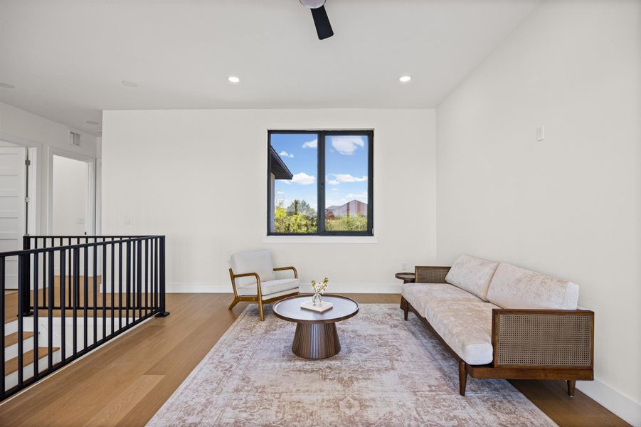 Sitting room with wood finished floors, a ceiling fan, recessed lighting, and an upstairs landing