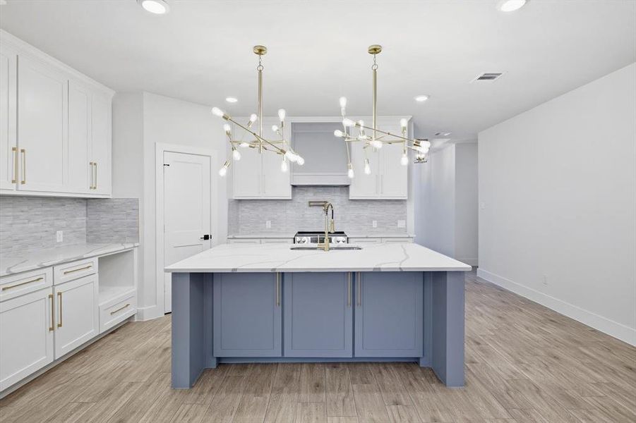 Kitchen with white cabinetry, light stone countertops, decorative light fixtures, light wood-style floors, and recessed lighting