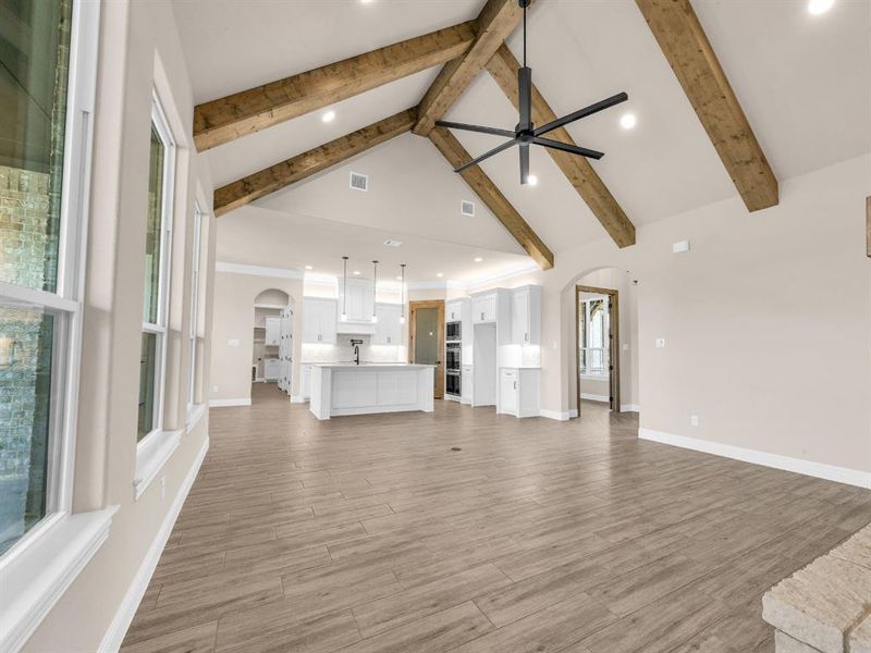 Unfurnished living room featuring high vaulted ceiling, ceiling fan, wood-type flooring, and a wealth of natural light