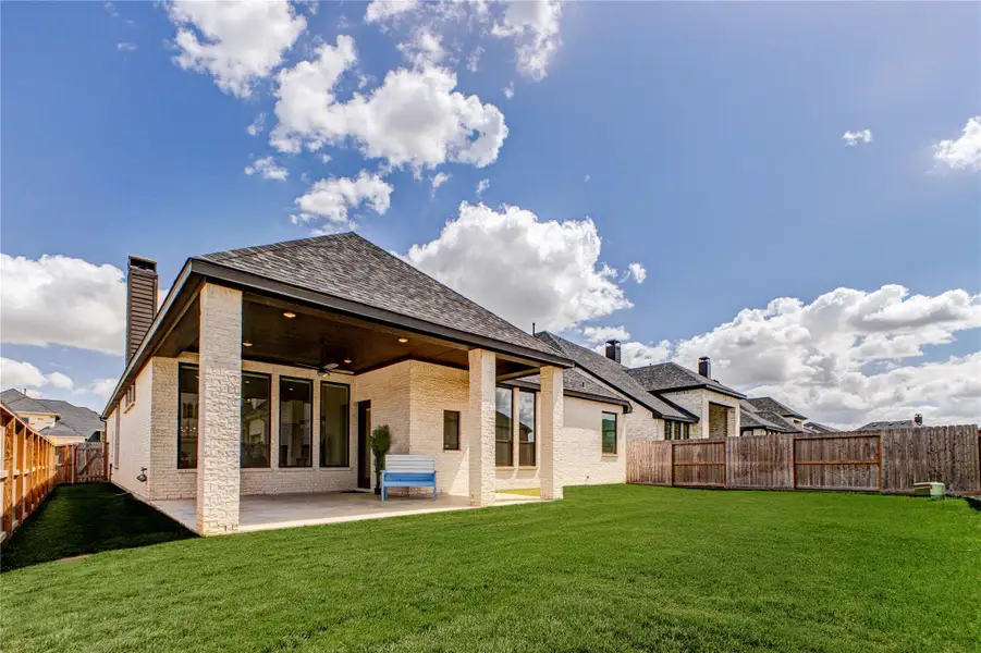 This photo showcases a modern home with a covered patio, large windows, and a spacious, well-maintained backyard. The exterior features light brick and a shingled roof, providing a clean and inviting look. Perfect for outdoor entertaining and relaxation. This photo showcases a modern home with a covered patio, large windows, and a spacious, well-maintained backyard. The exterior features light brick and a shingled roof, providing a clean and inviting look. Perfect for outdoor entertaining and relaxation.