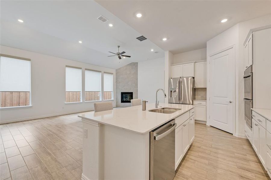 Kitchen featuring stainless steel appliances, vaulted ceiling, ceiling fan, a center island with sink, and open floor plan Kitchen featuring stainless steel appliances, vaulted ceiling, ceiling fan, a center island with sink, and open floor plan