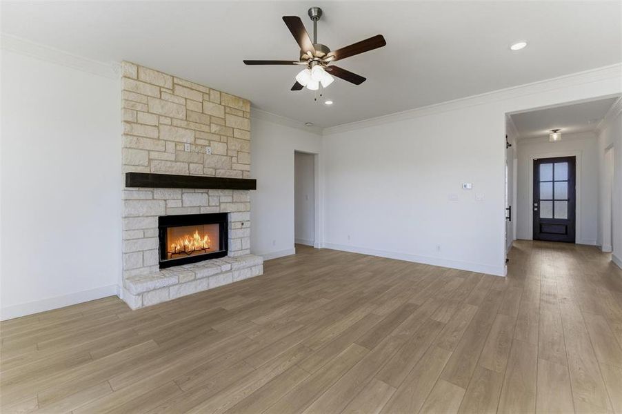 Unfurnished living room with ceiling fan, a fireplace, crown molding, light wood-style flooring, and recessed lighting