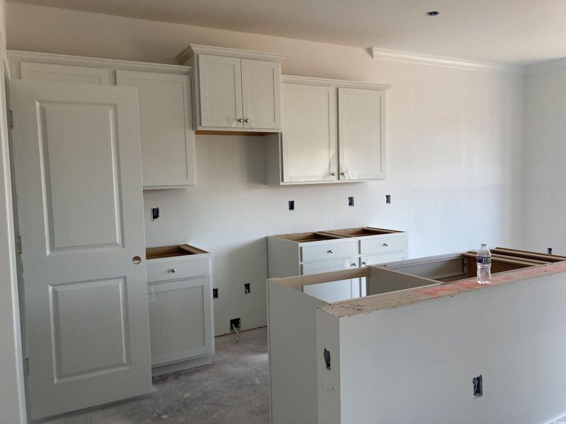 Kitchen featuring white cabinets, concrete floors, a kitchen island, and ornamental molding Kitchen featuring white cabinets, concrete floors, a kitchen island, and ornamental molding
