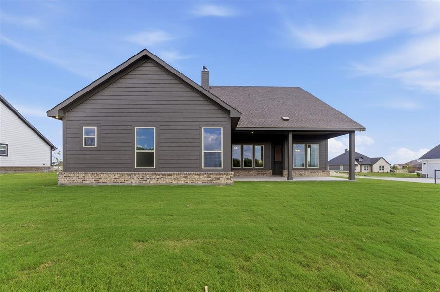 Rear view of property with brick siding, a patio, a yard, and roof with shingles Rear view of property with brick siding, a patio, a yard, and roof with shingles