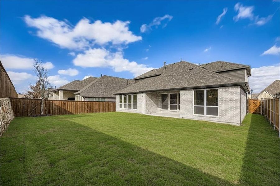Rear view of house with a patio, brick siding, a fenced backyard, and roof with shingles