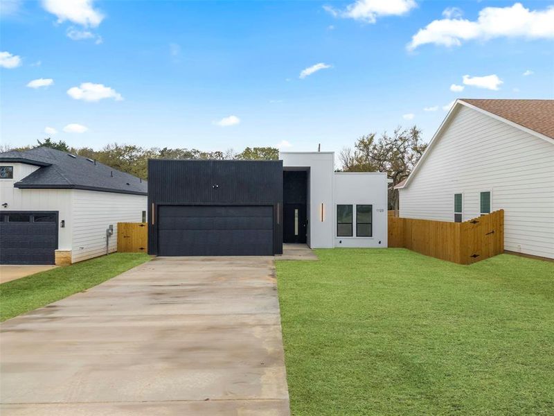 Contemporary home featuring driveway, an attached garage, and a gate
