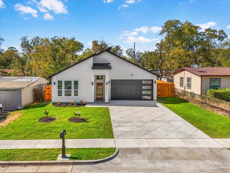View of front of house featuring concrete driveway, stucco siding, and an attached garage