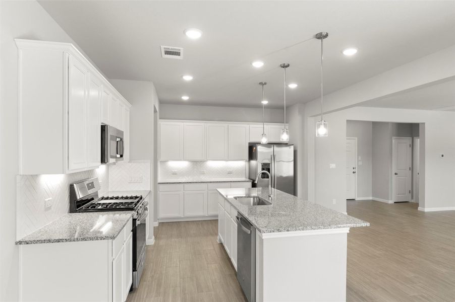 Kitchen with stainless steel appliances, a sink, tasteful backsplash, light wood finished floors, and recessed lighting
