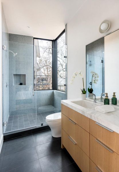 A well-lit primary bathroom features a glass-enclosed shower, a sleek vanity, and large windows. A well-lit primary bathroom features a glass-enclosed shower, a sleek vanity, and large windows.