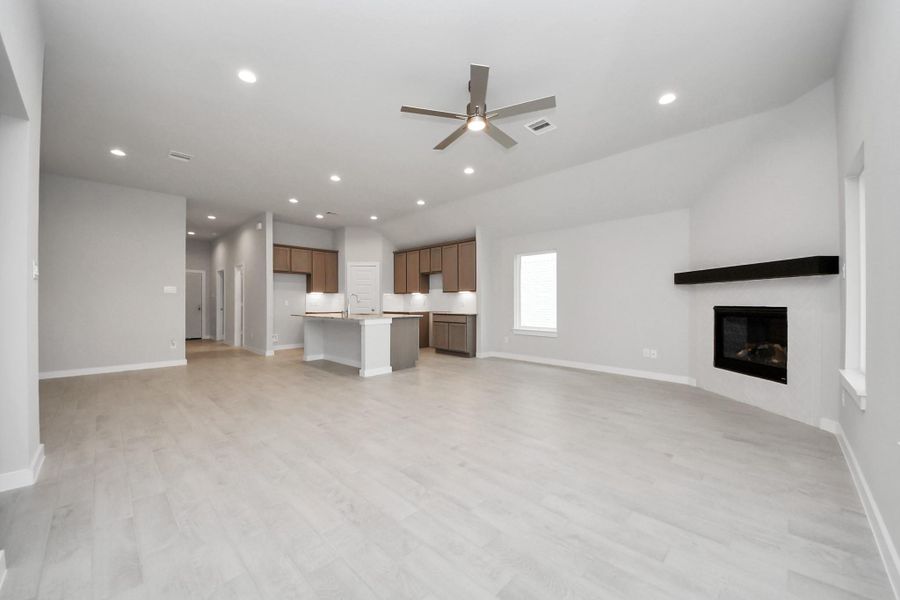 Welcome family and guests to your charming living room! With its high ceilings, recessed lighting, ceiling fan, custom paint, beautiful flooring, and large windows that let in abundant natural light, this room is perfect for gatherings. Sample photo of completed home with similar floor plan. Actual colors and selections may vary.