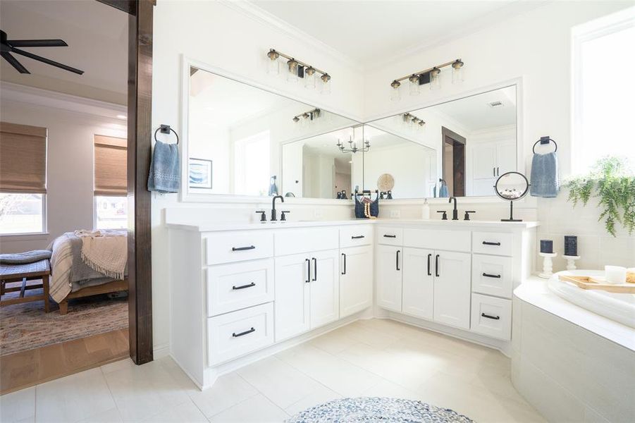 Ensuite bathroom featuring double vanity, crown molding, a bath, ceiling fan, and hanging lights Ensuite bathroom featuring double vanity, crown molding, a bath, ceiling fan, and hanging lights