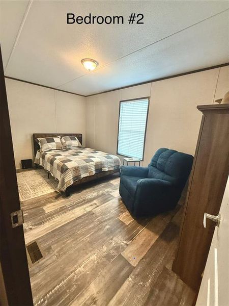 Bedroom with wood finished floors and a textured ceiling