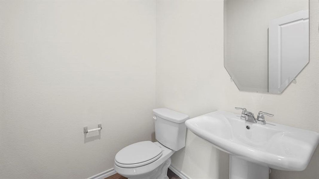 Pedestal sink with chrome fixtures and an octagonal mirror