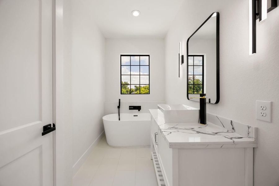 The spa-like primary bath features a free standing soaking tub, natural light, an additional vanity, and a private water closet.