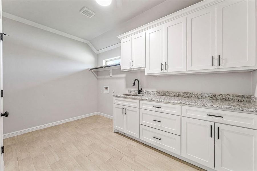 Laundry room with crown molding, hookup for a washing machine, light wood-type flooring, and cabinet space